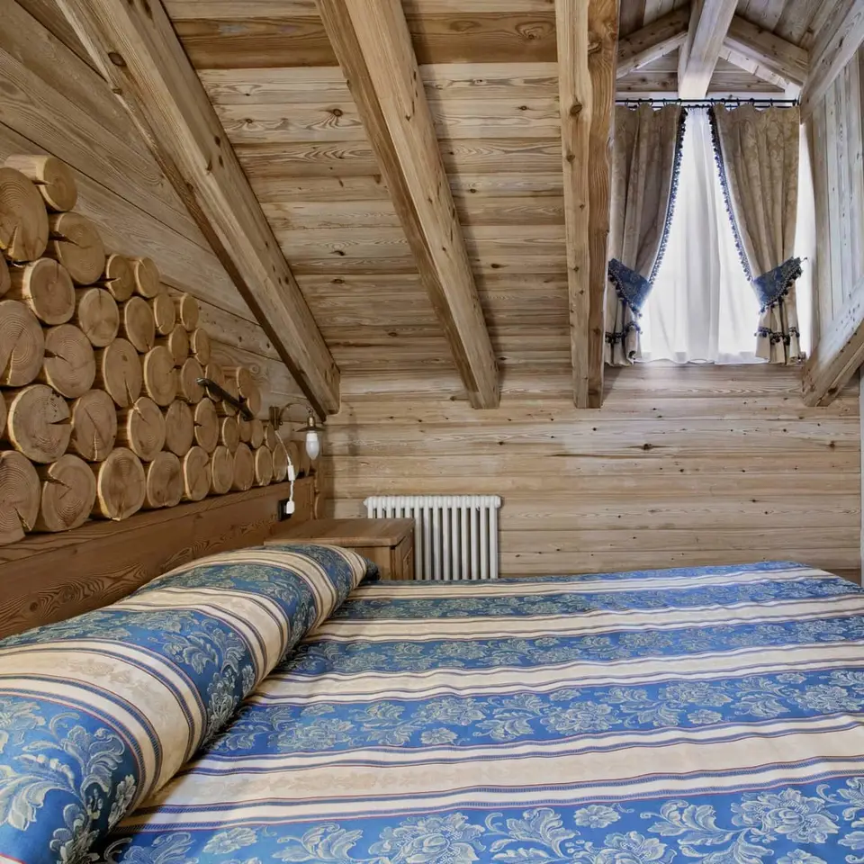 Letto della suite Galileo Galilei con la parete di tronchi