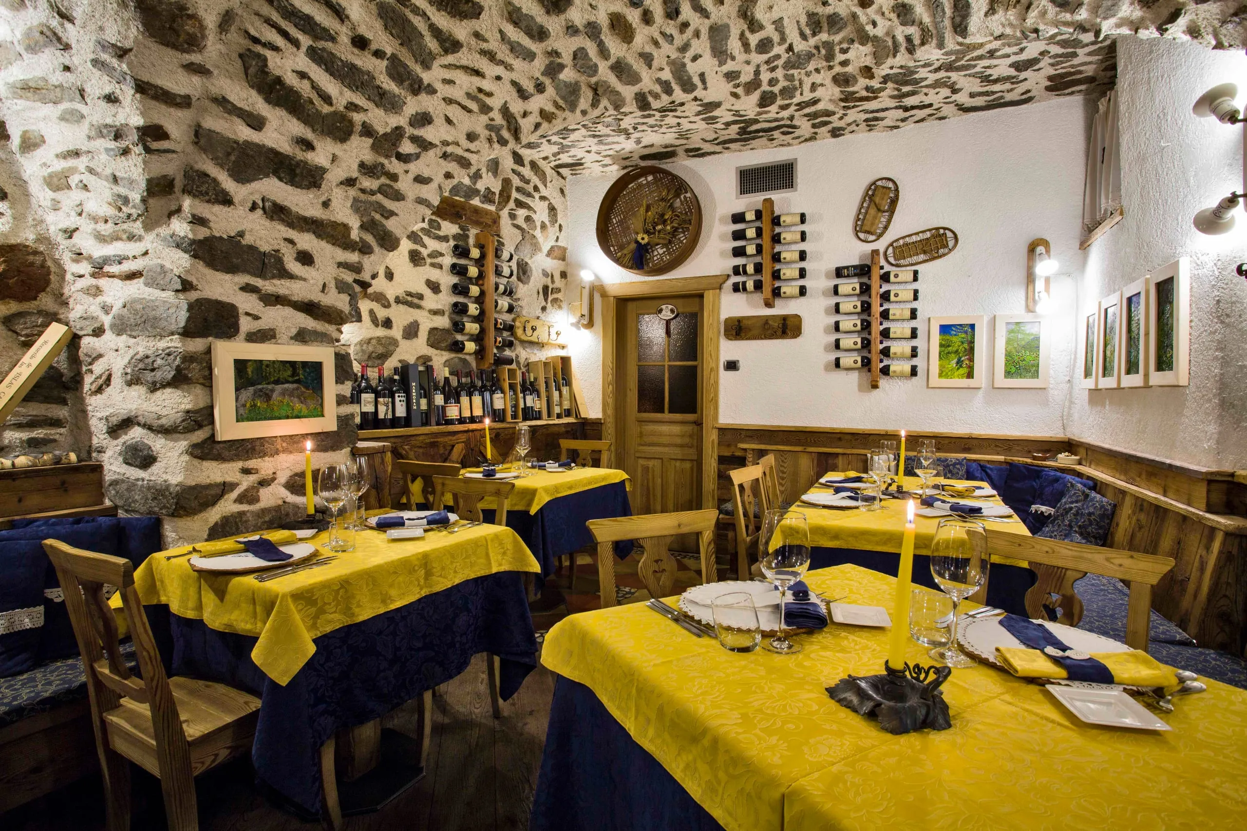 Sala dell'osteria sotto le volte in pietra, con le tovaglie gialle