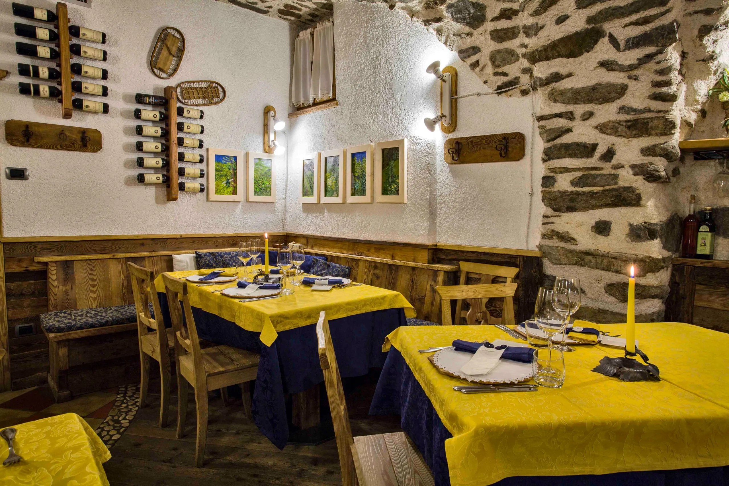 Sala dell'osteria con i tavoli apparecchiati e le bottiglie alla parete