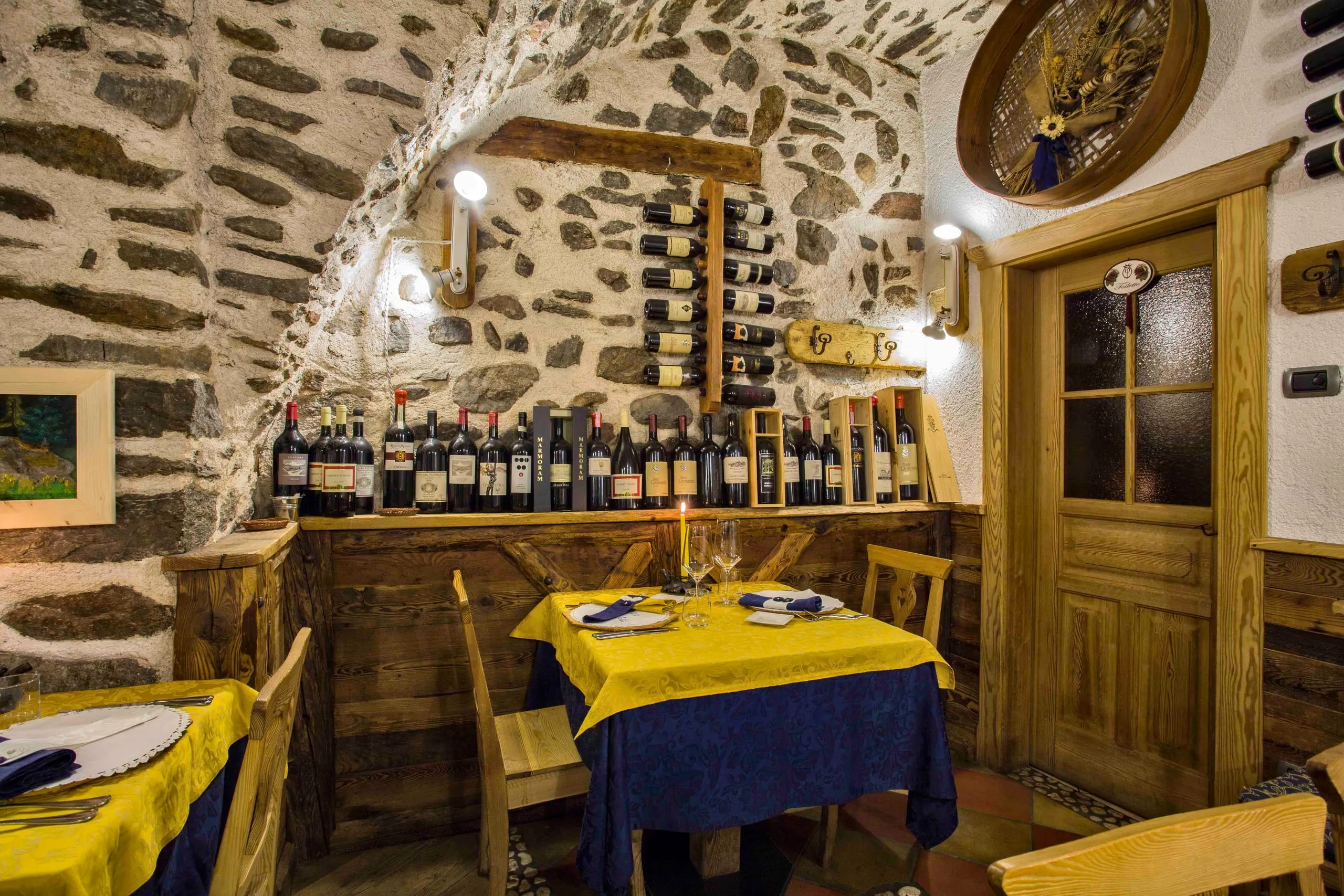 Tavoli dell'osteria davanti alla porta in legno e alla parete di bottiglie
