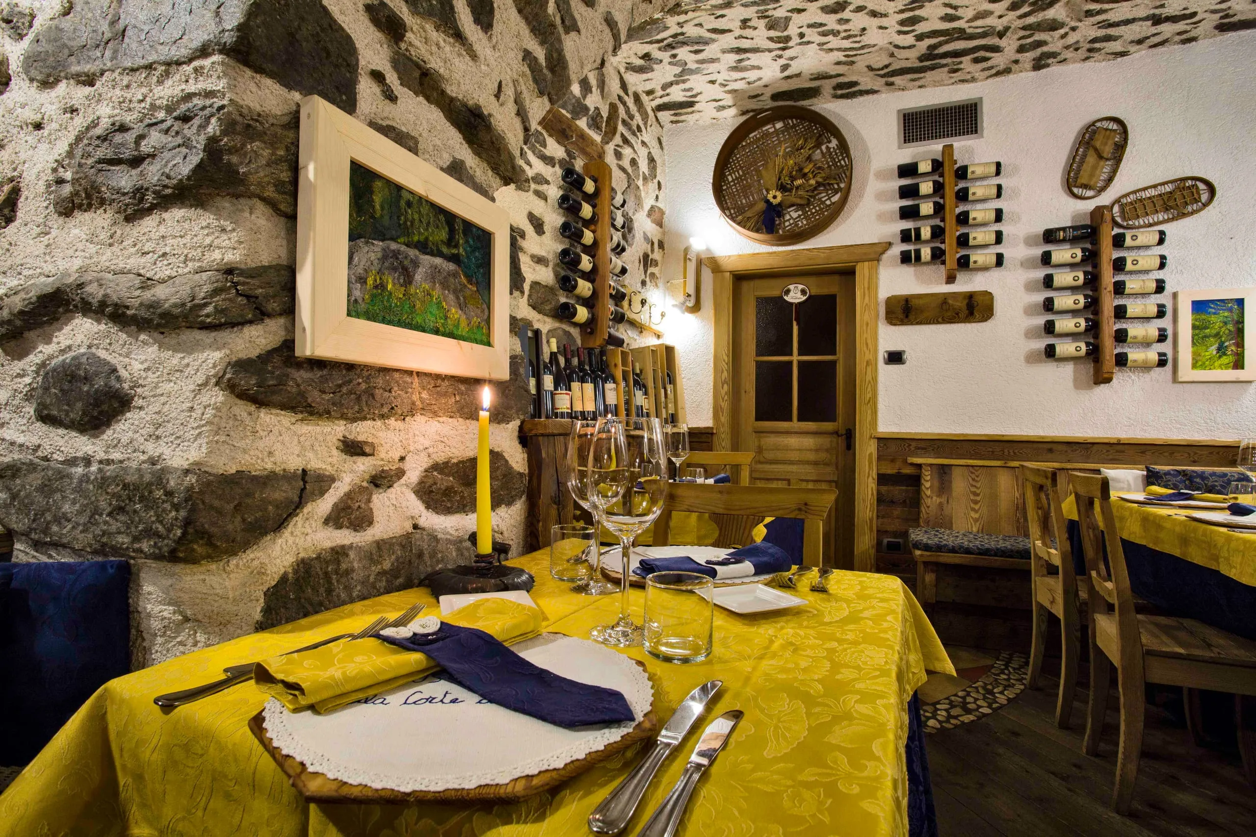 Tavolo apparecchiato in primo piano, con la sala dell'osteria sullo sfondo