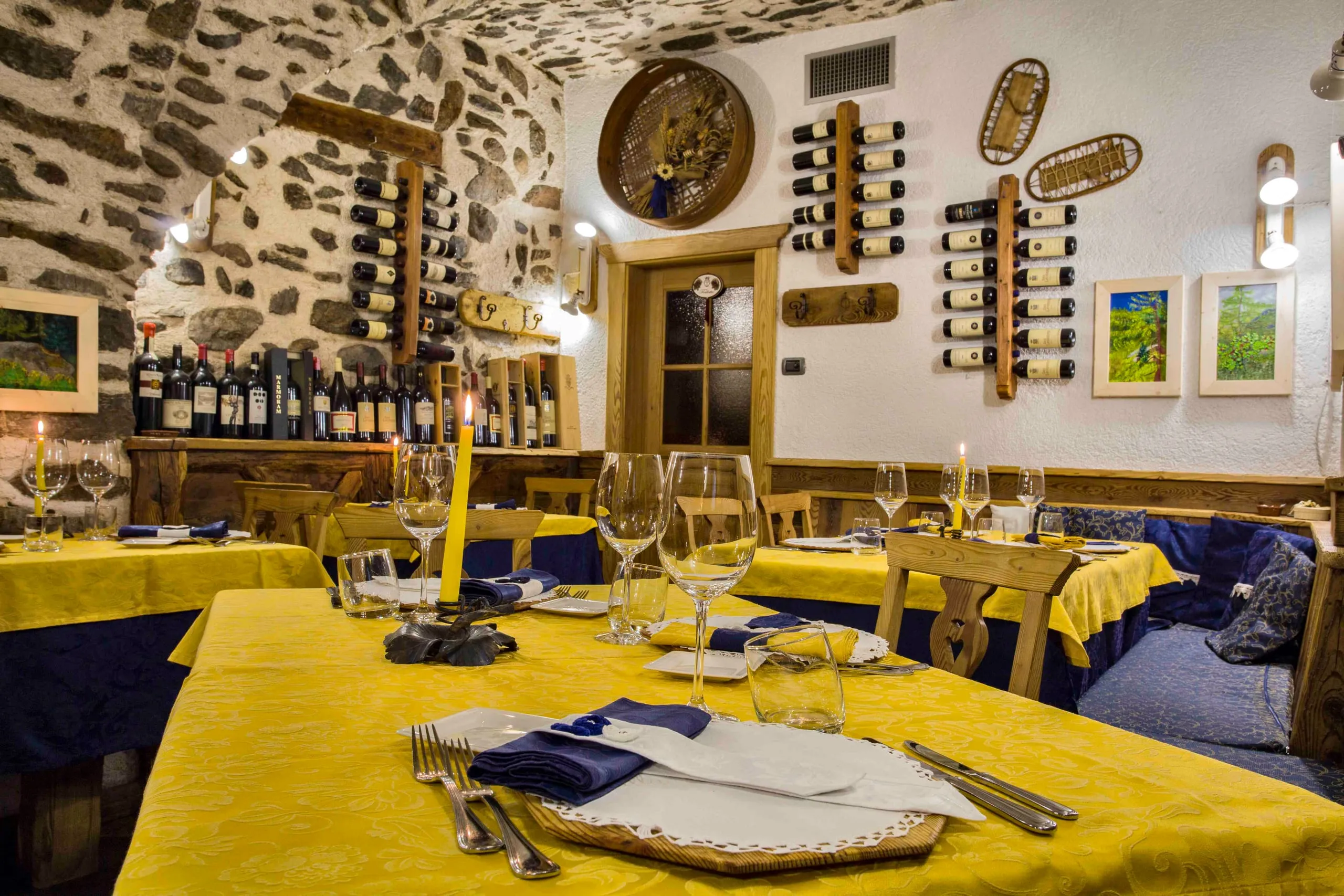 Tavolo apparecchiato con calici e candela nella sala dell'osteria