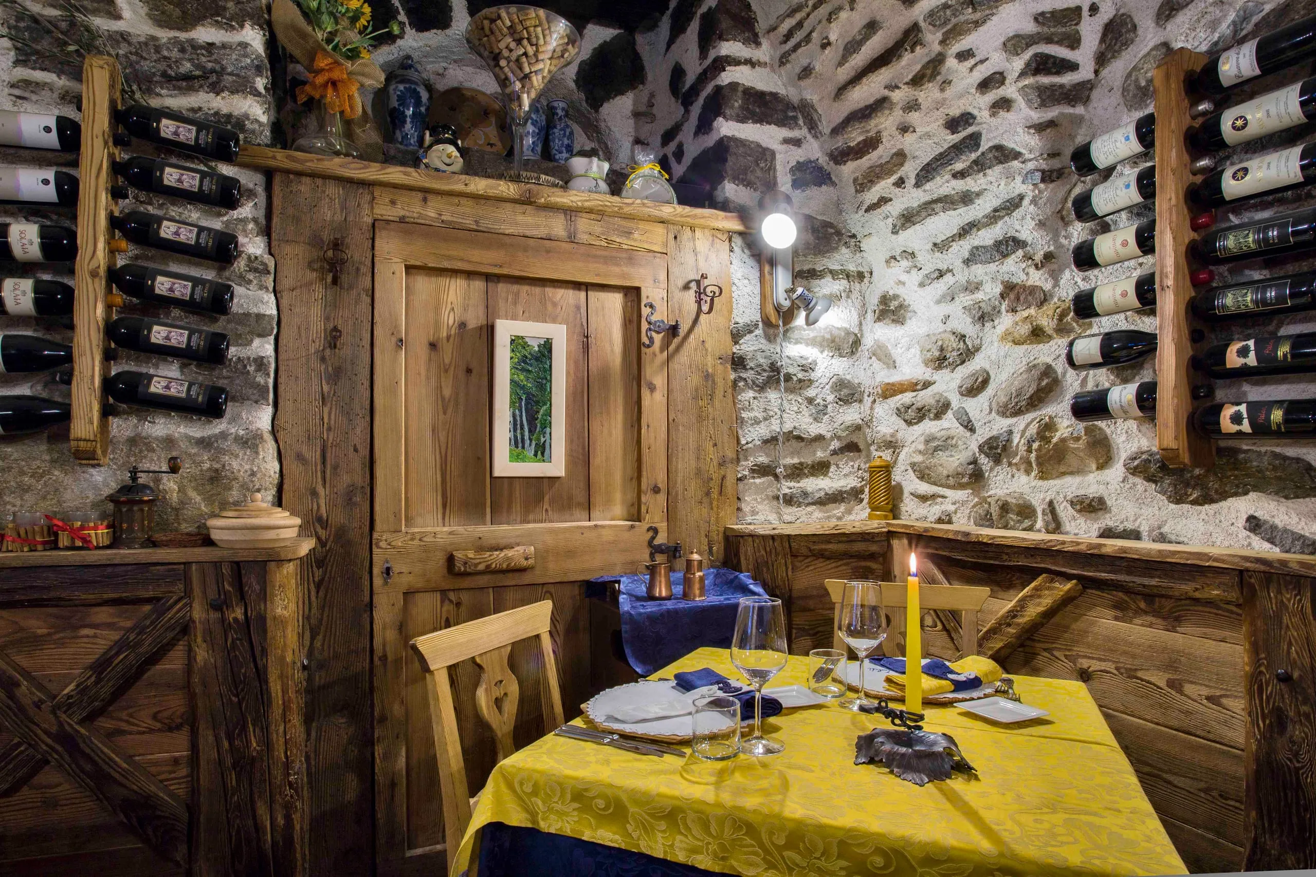 Tavolo accanto alla porta in legno, tra le bottiglie e la pietra