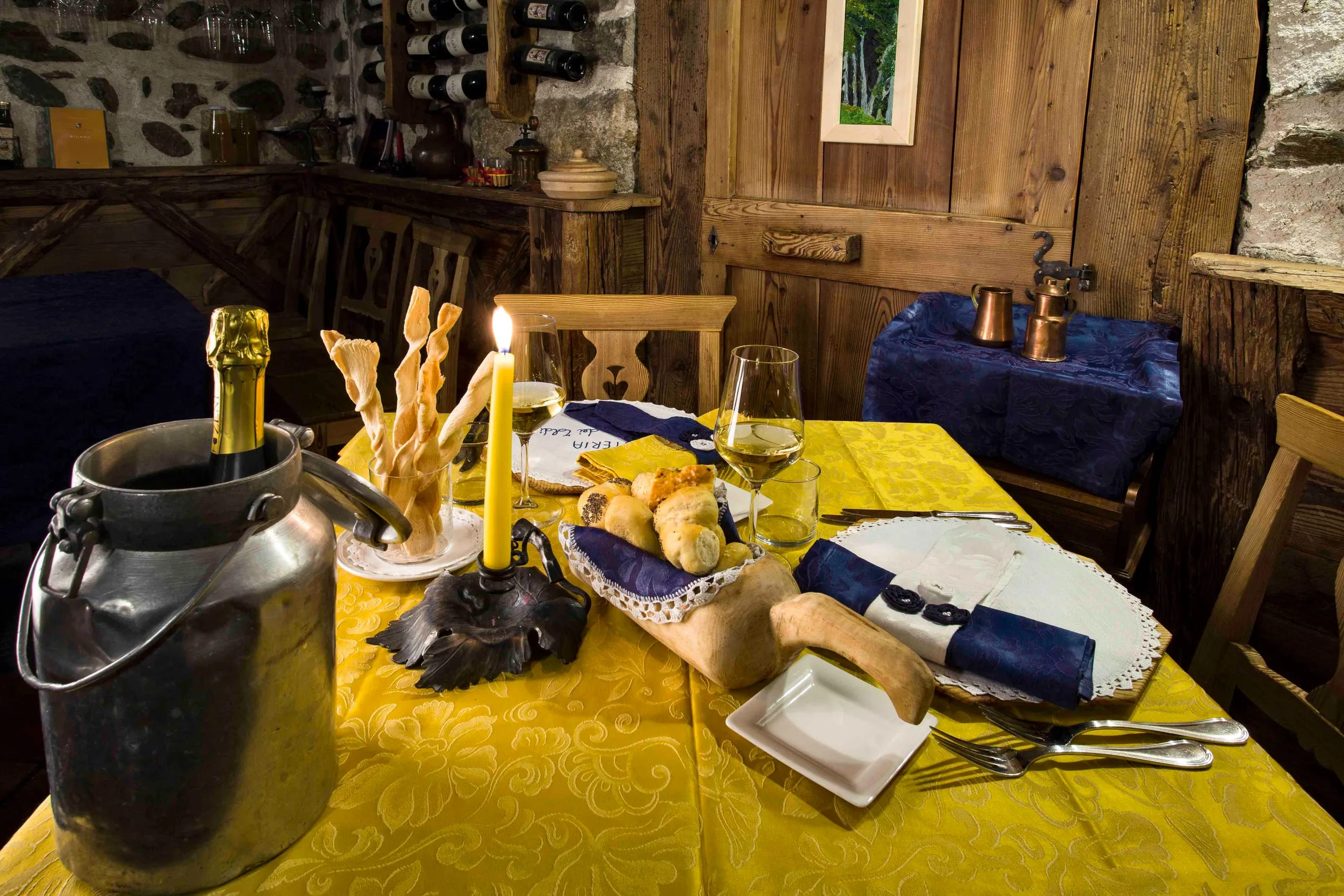 Tavolo apparecchiato con pane, grissini e il vino in fresco