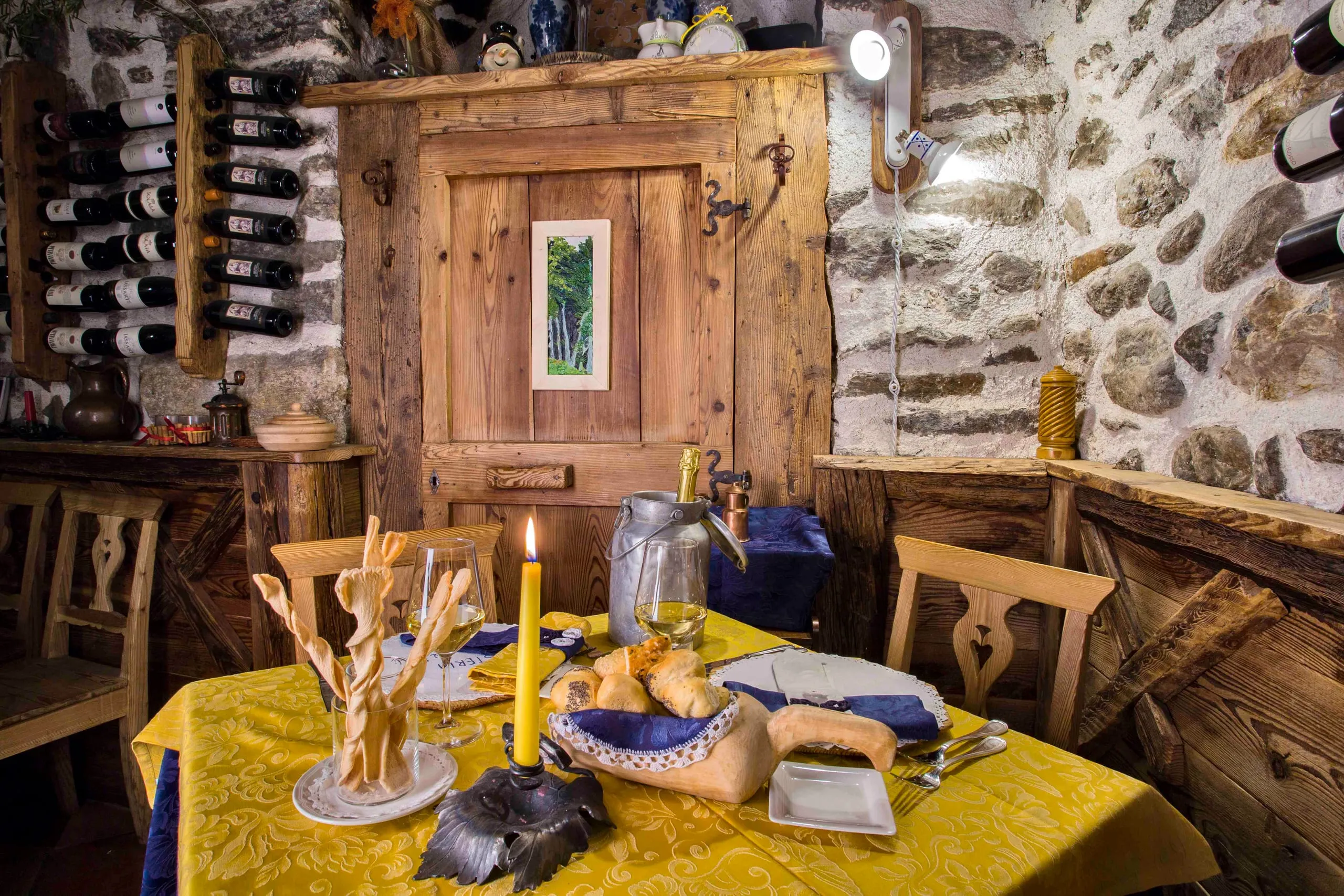 Tavolo apparecchiato davanti alla porta in legno e alla parete di bottiglie