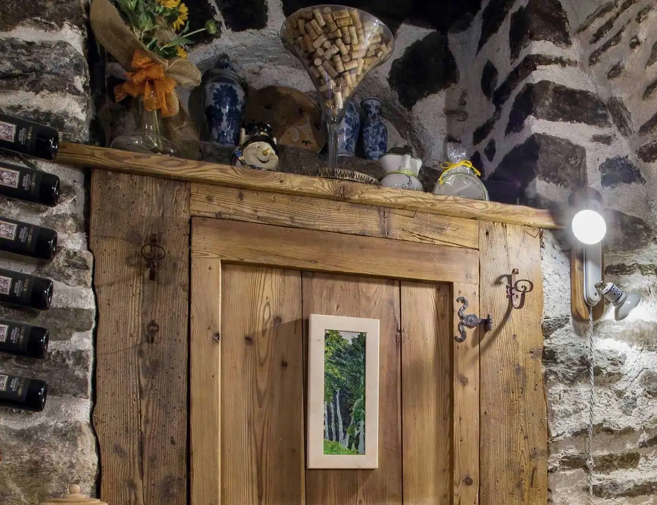 La porta in larice tra le bottiglie e la pietra