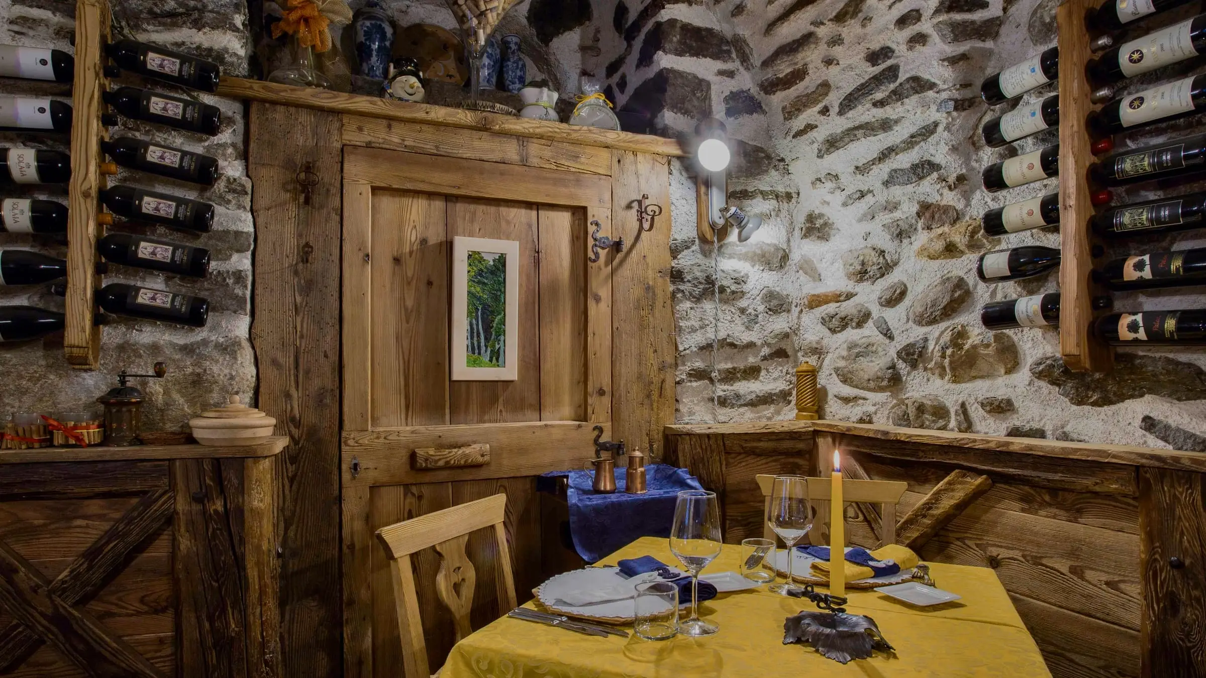 Tavolo accanto alla porta in legno, tra le bottiglie e la pietra