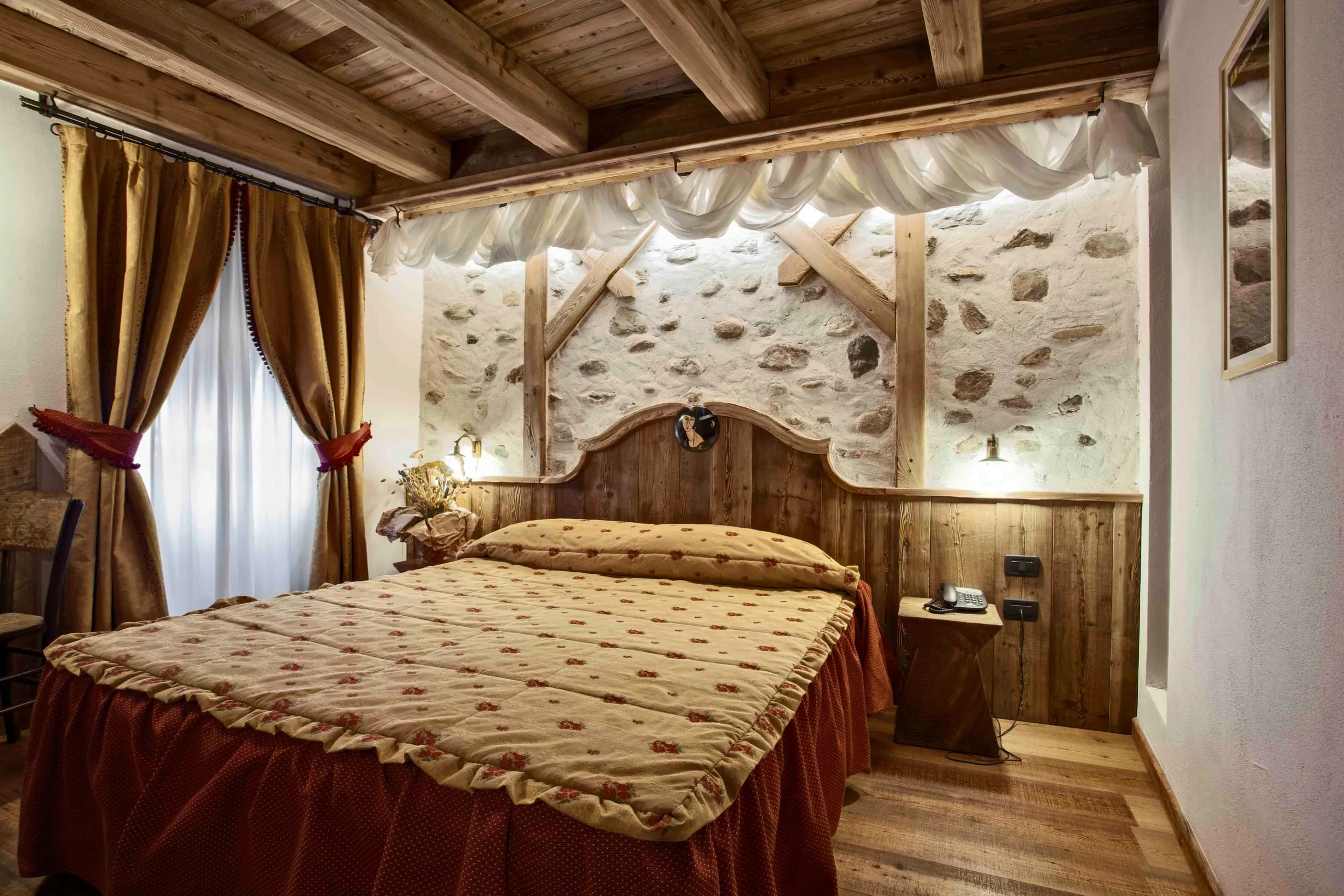 Letto della suite Amedeo Modigliani davanti alla parete in pietra
