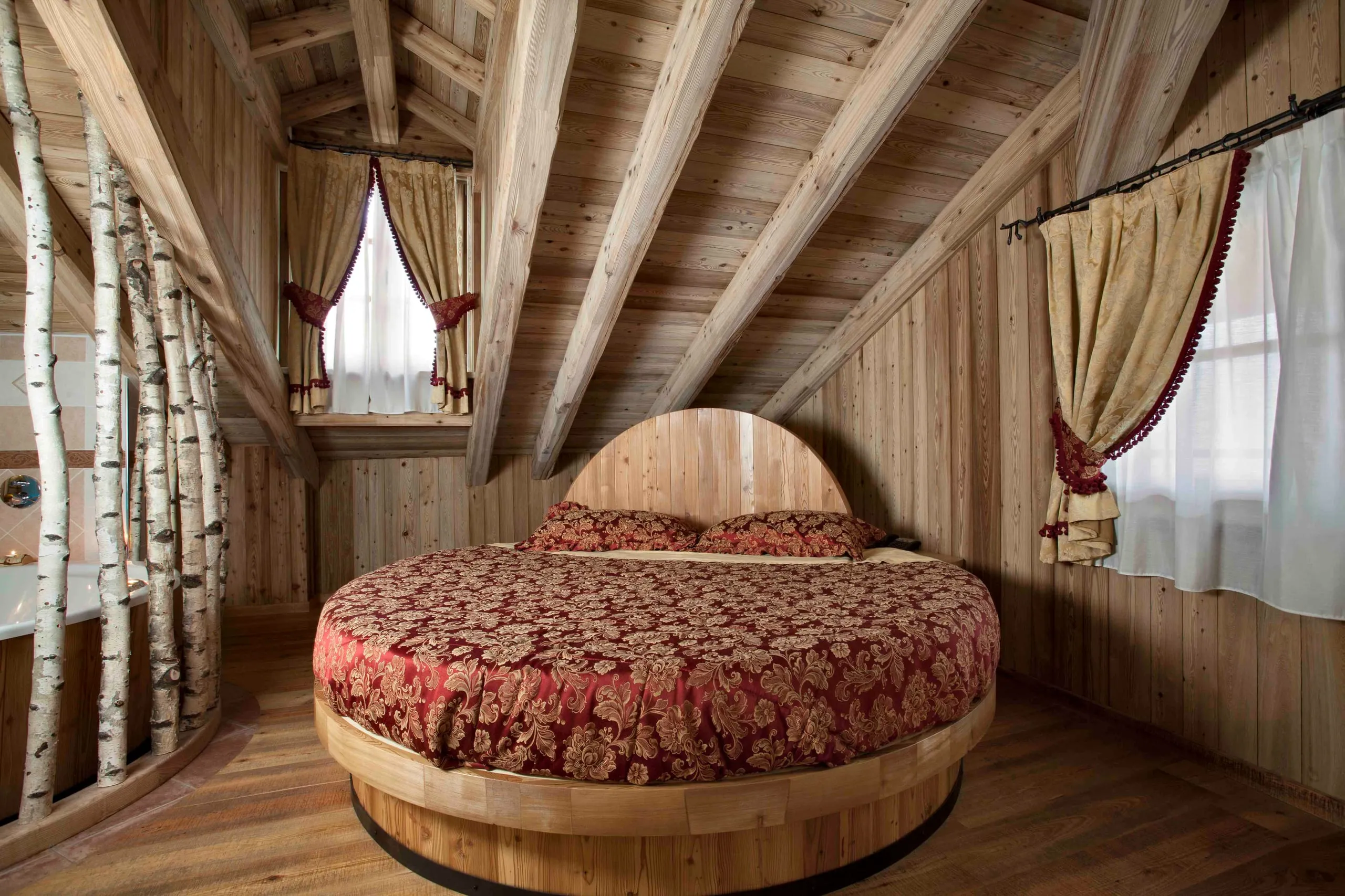 Letto rotondo della suite Archimede tra i tronchi di betulla