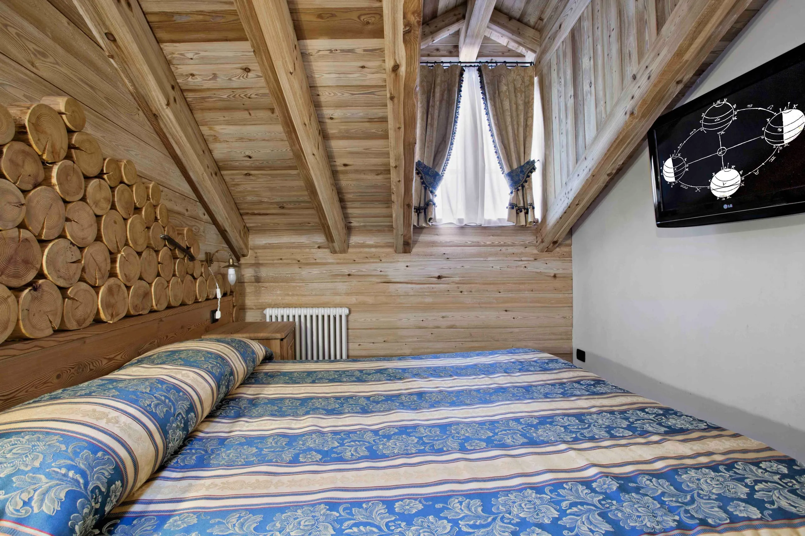 Letto della suite Galileo Galilei con la parete di tronchi
